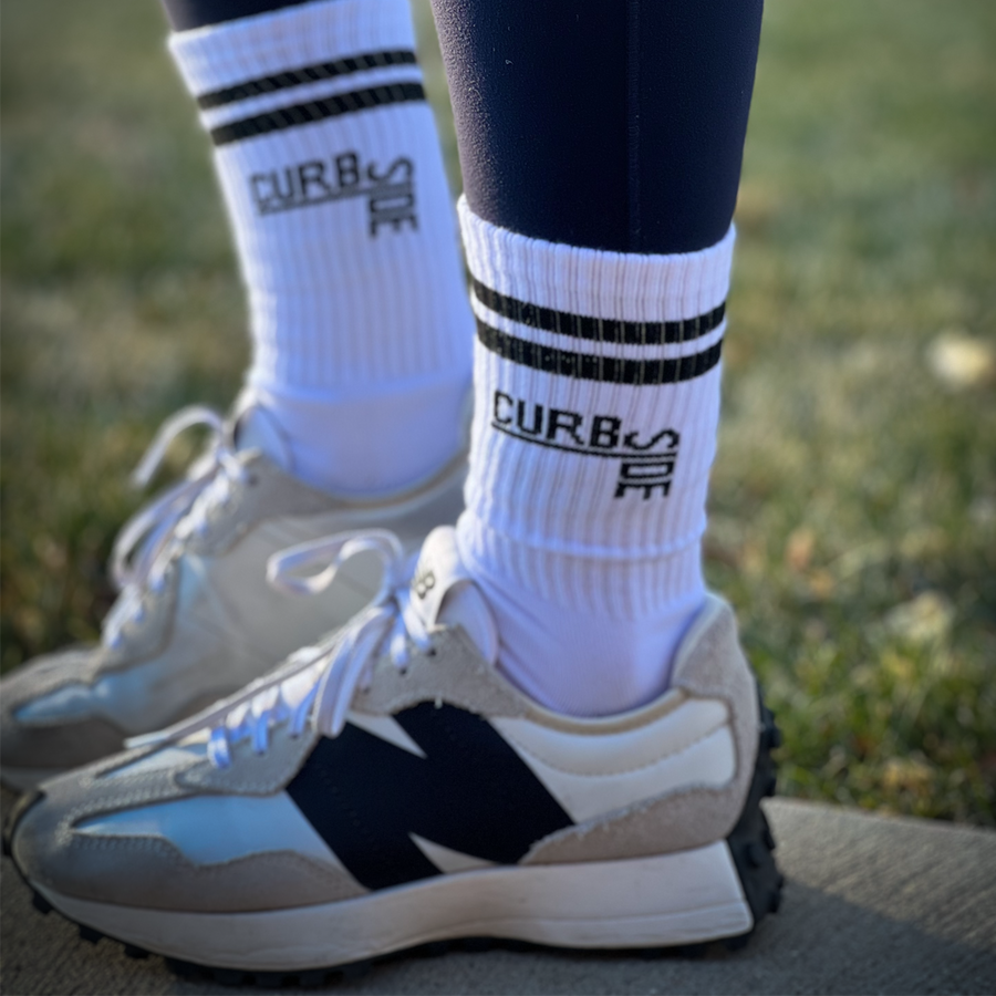 Woman wearing cute curbside black and white strip classic crew socks wearing new balance sneakers