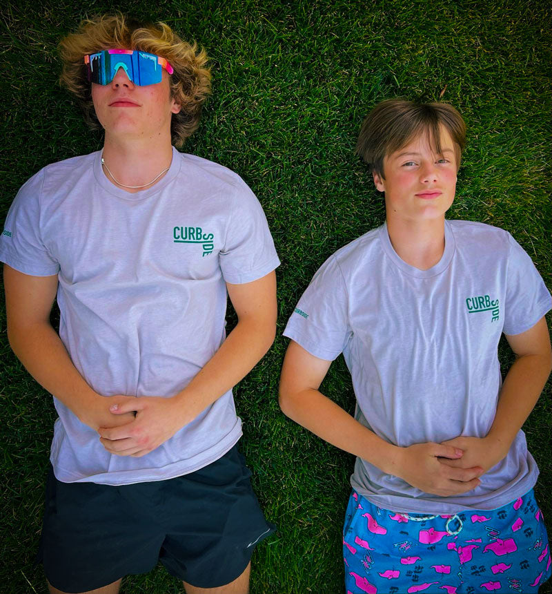 Teenage boys lying in the grass wearing sunglasses and soft curbside t shirts