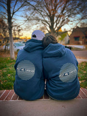 BFF best friends sitting together on stoop wearing super soft, relaxed fit navy blue graphic hoodie with meet me curbside on the back